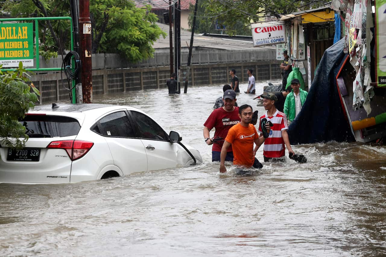 Indonesian people wade through floodwaters in Jakarta, Indonesia.