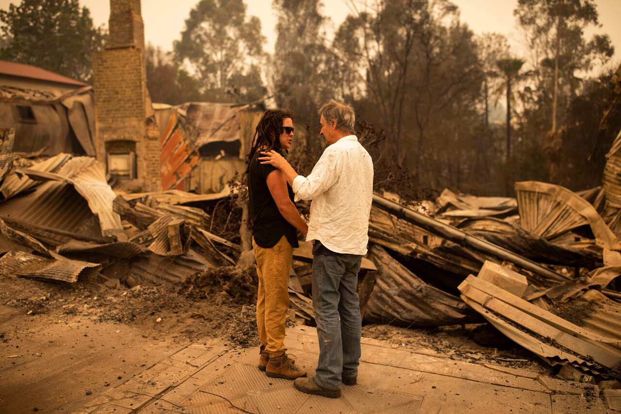 Business owner Sally Anne Wilson in front of her destroyed shop with her partner Christopher Lee in Cobargo, NSW.