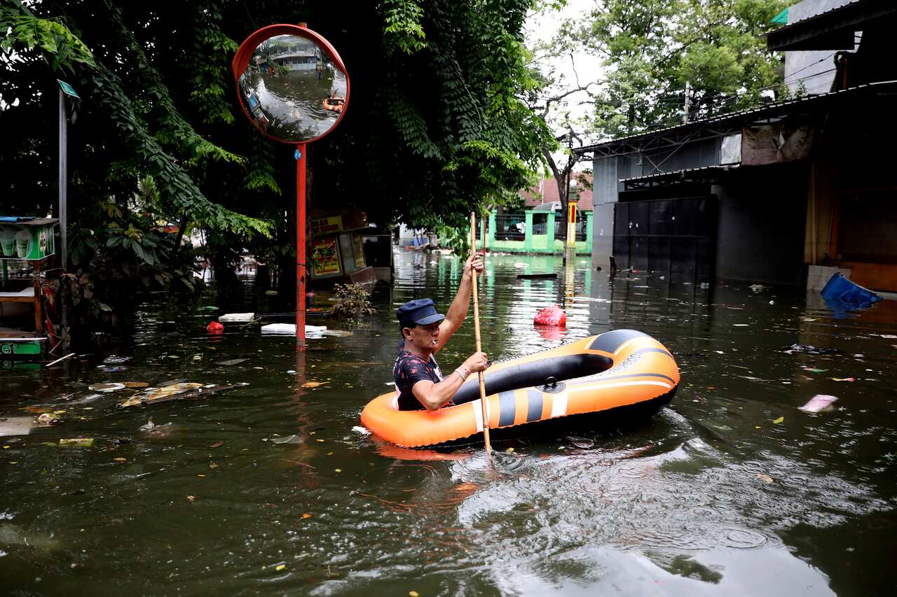 A man navigates an inflatable boat at a flooded neighborhood in Jakarta, Indonesia.