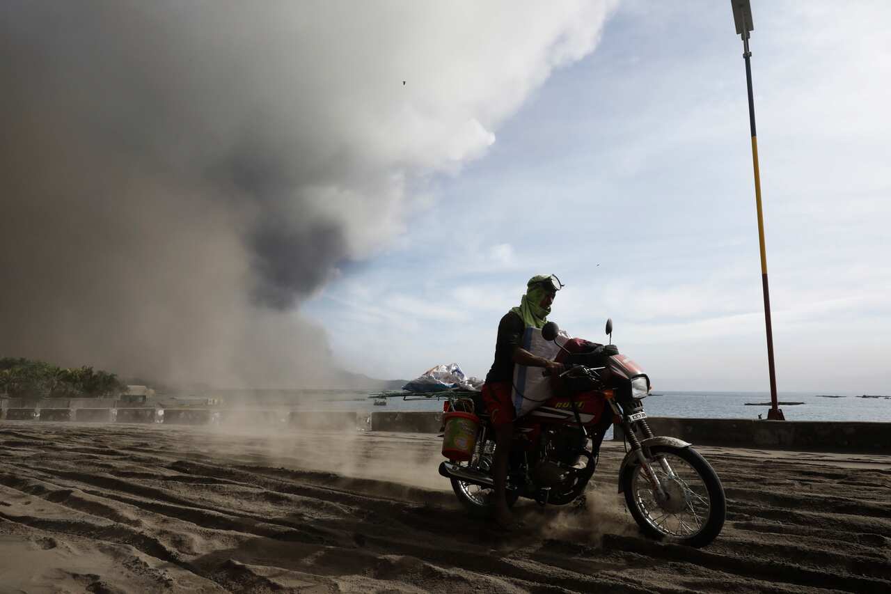 A person rides a motobike on a road covered in ash deposits, a day after the eruption of Taal Volcano, in Agoncillo town in Batangas province, Philippines.