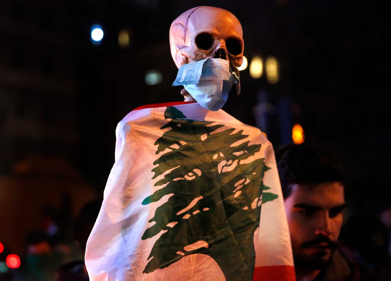 An anti-government protester carries a skeleton wrapped in a Lebanese flag.