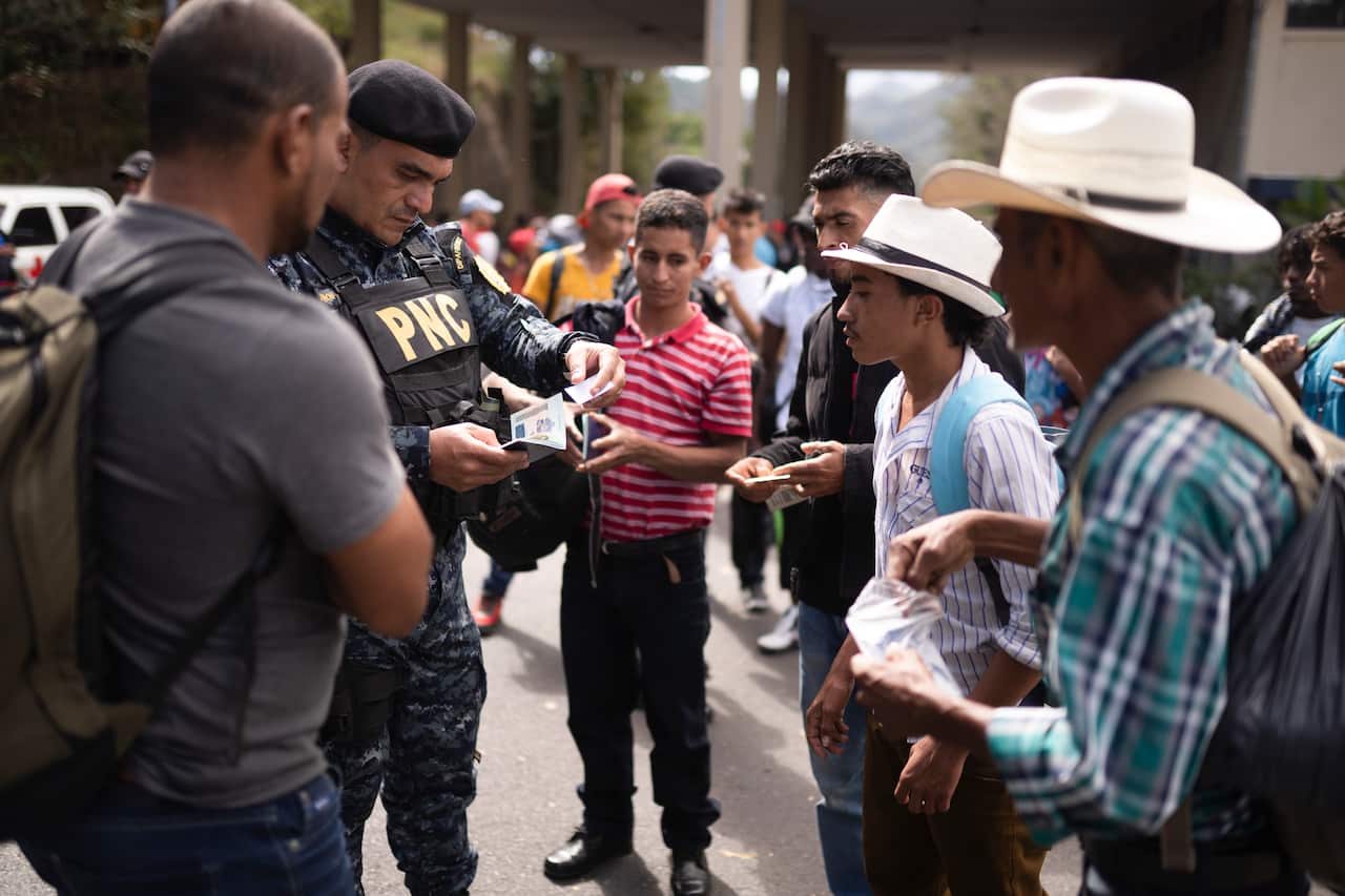 A Guatemalan police officer checks migrants' documentation at a border checkpoint in Agua Caliente.
