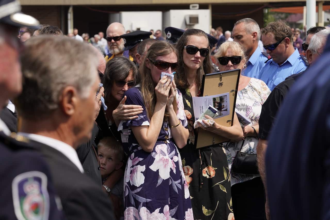 Sam's widow, Megan wipes away tears as she watches the casket being loaded into the hearse.