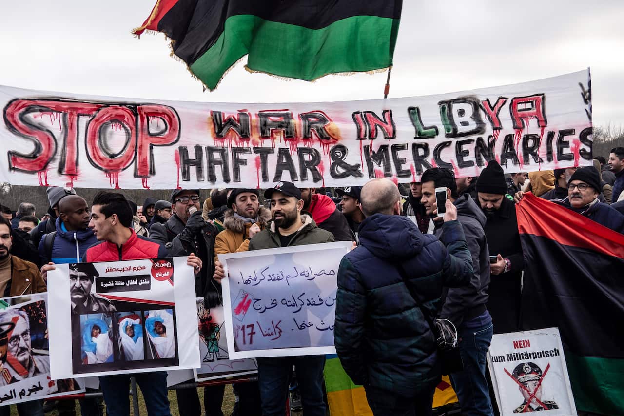 19 January 2020, Berlin: People hold banners and placards as they take part in a protest against Libyan strongman Khalifa Haftar, leader of the self-styled Libyan National Army, during the International conference on Libya. Photo: Paul Zinken/dpa