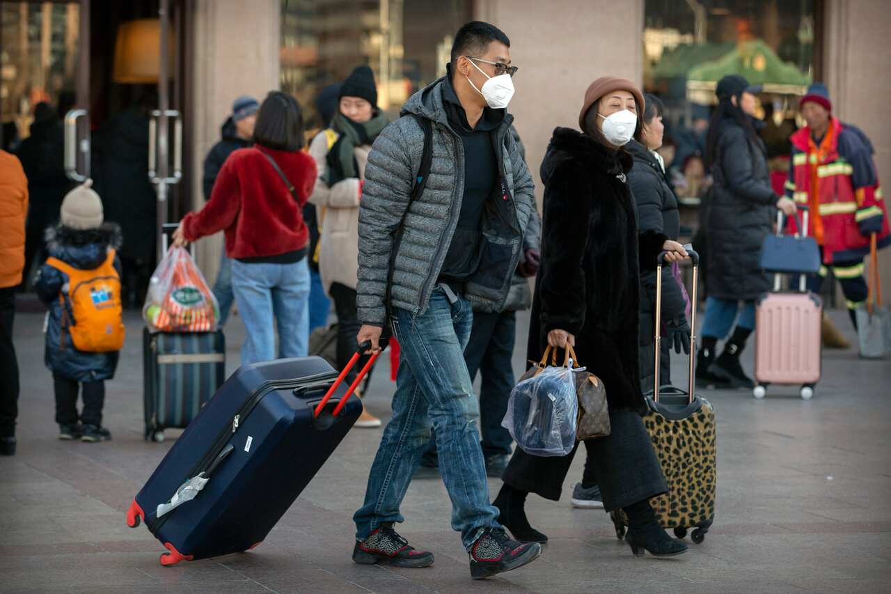 Travelers wear face masks as they walk outside of the Beijing Railway Station in Beijing.