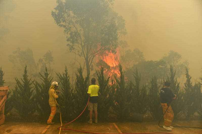 Workers and firefighters try to extinguish a blaze 10km west of Canberra.