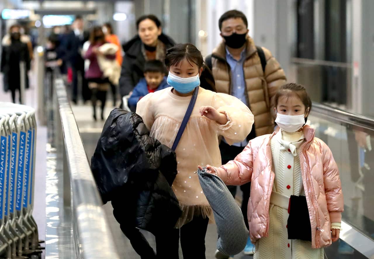 Passengers wearing masks walk towards a quarantine inspection after a flight arrived from Wuhan at Narita International Airport, Tokyo.