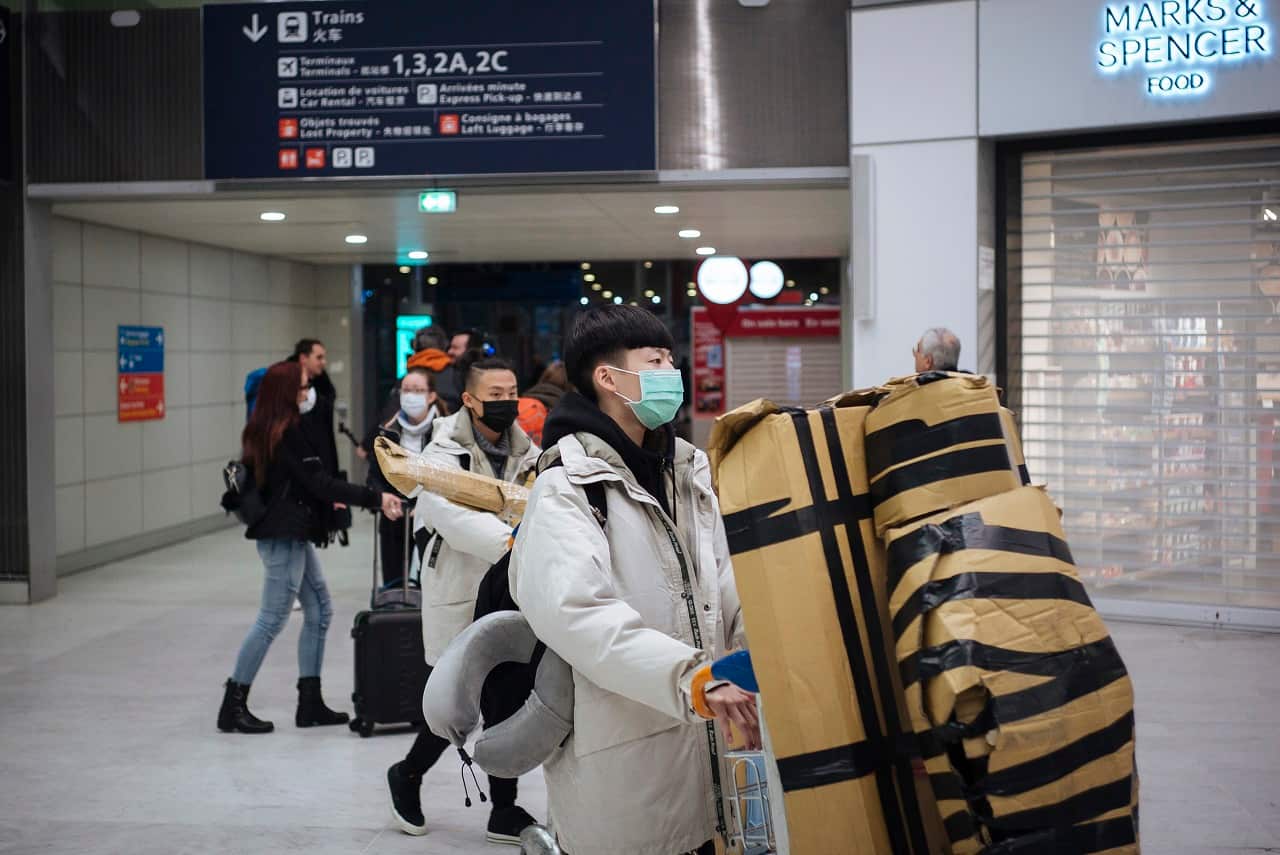 Travelers coming from Beijing and wearing a mask arrive at Charles de Gaulle airport in Paris.