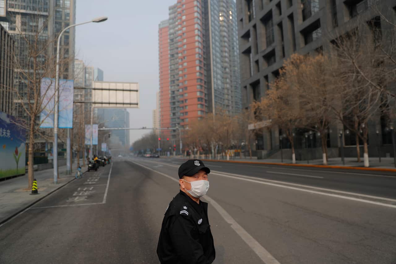 A security guard wears a mask in an empty street of Beijing
