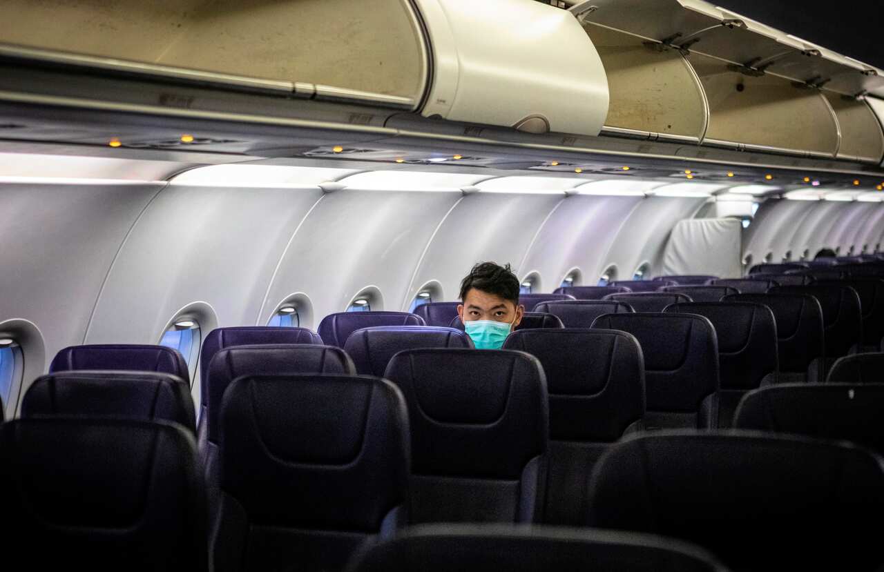 A passengers sits in a mostly empty airplane wearing protection mask against the coronavirus during a flight bound for Guangzhou, Guangdong Province, China.