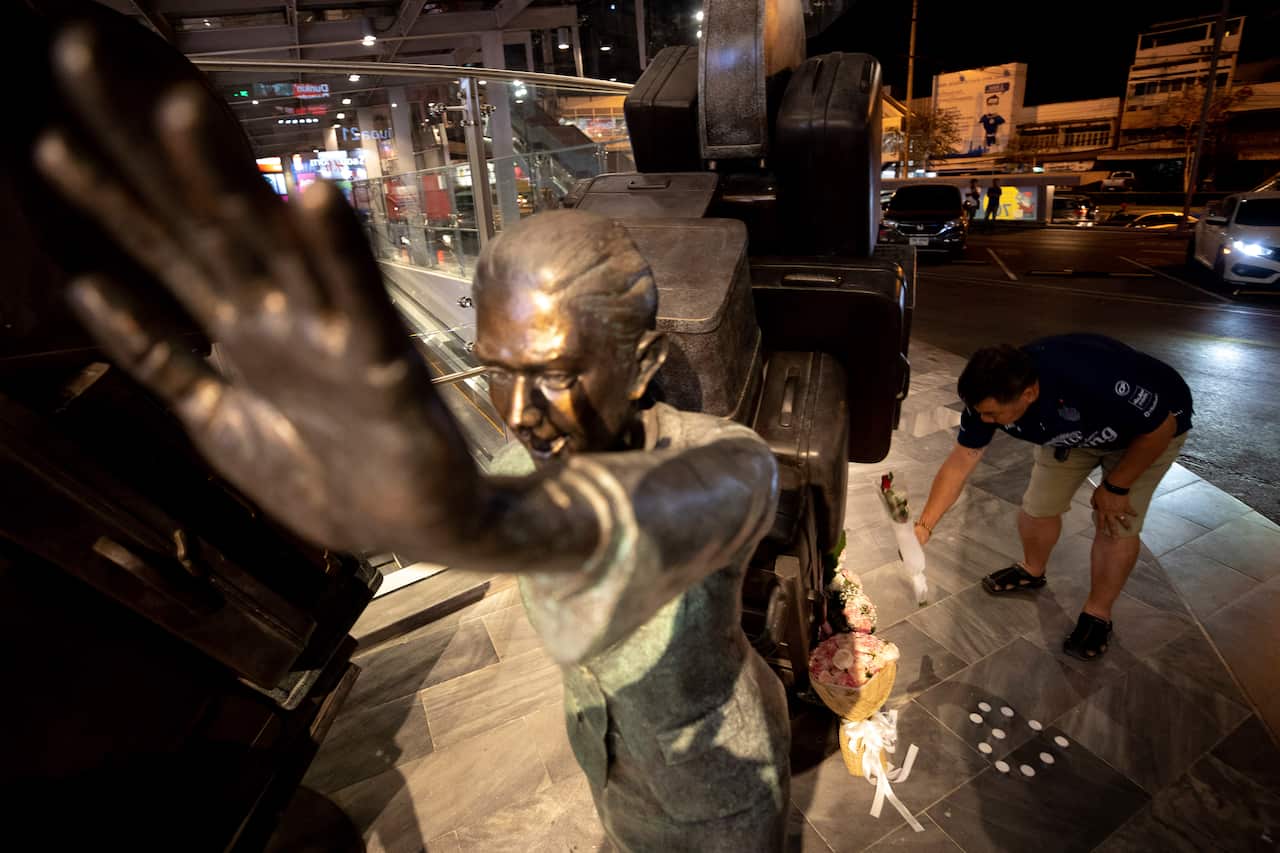 A man lays down flowers front of Sculpture during memorial service at Terminal 21 Korat mall in Nakhon Ratchasima, Thailand.