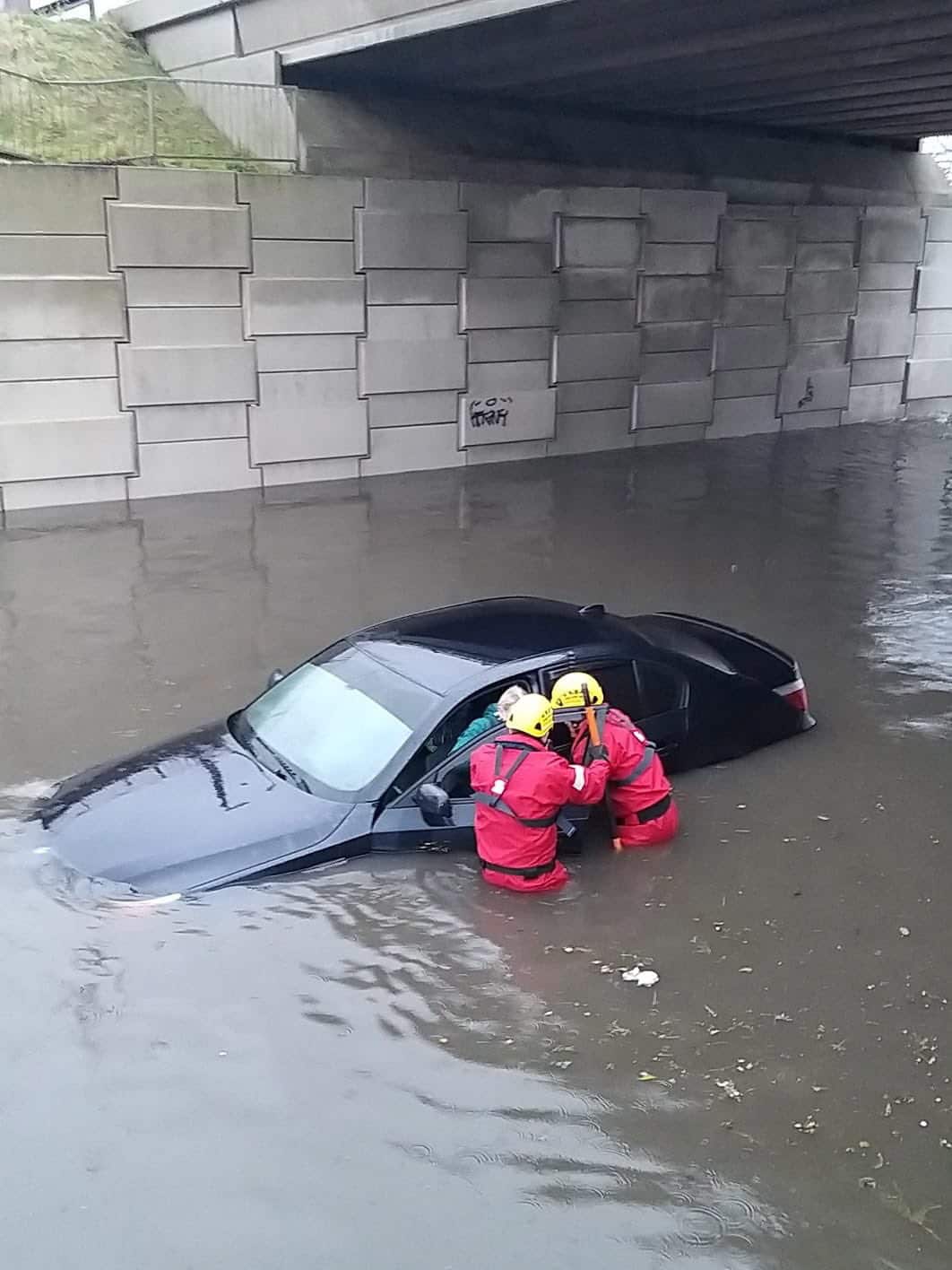 Fire station personnel assisting a motorist stranded in flood waters under a bridge to get out of the car in Blackpool, Britain, 9 February 2020.