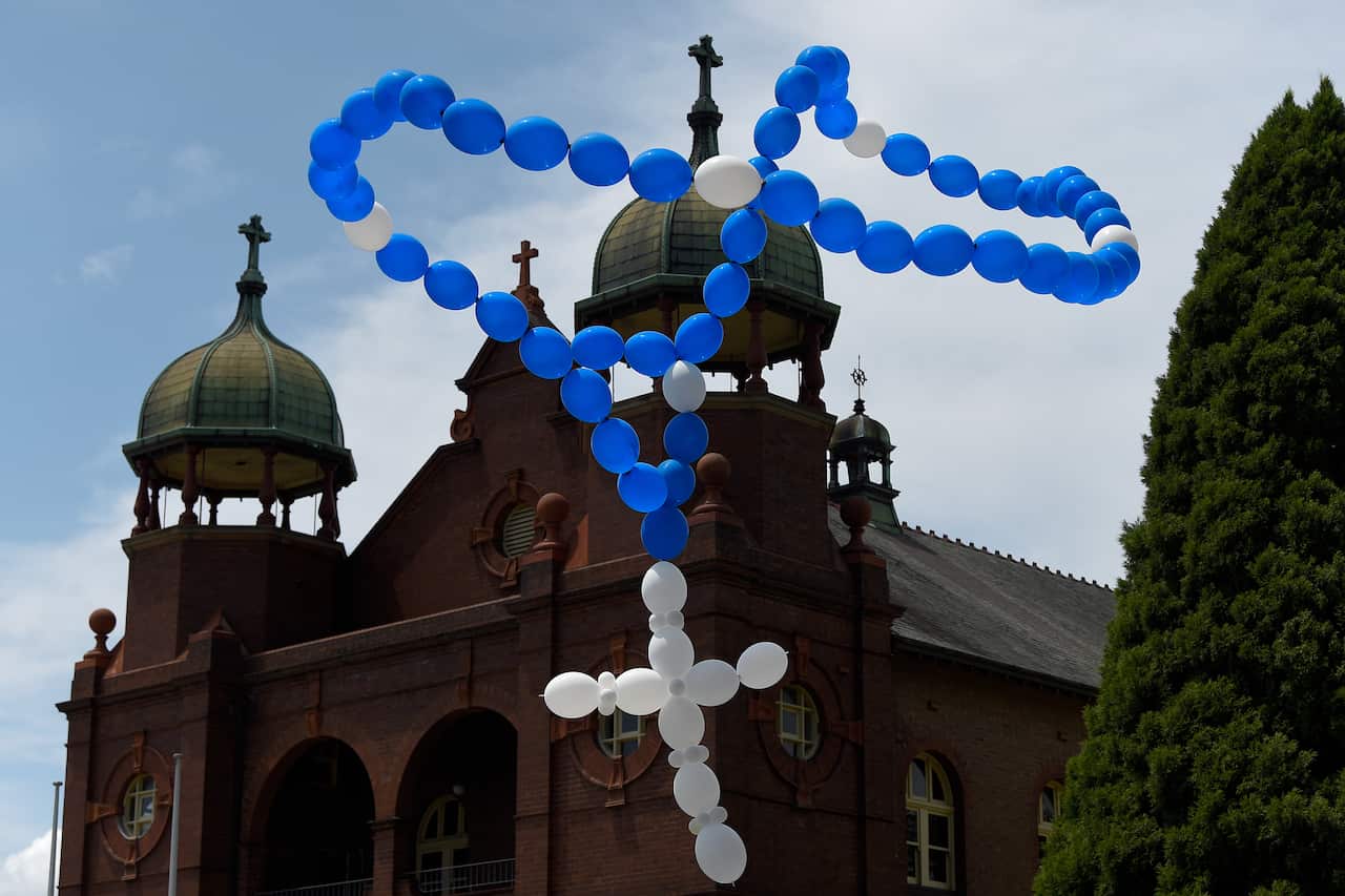 Balloons in the shape of Rosary beads are released during the funeral.
