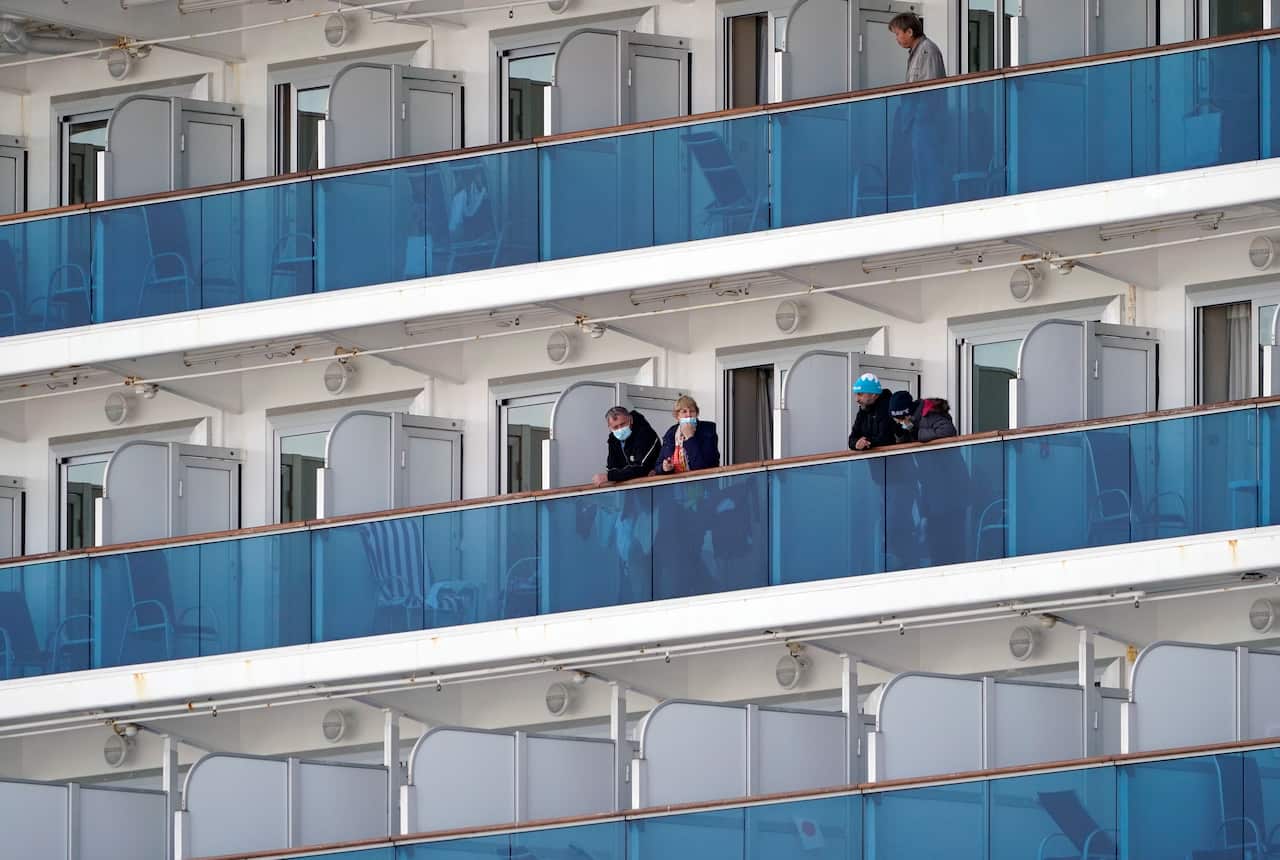 Passengers of the Diamond Princess cruise ship stand on their cabin's balconies at the Daikoku Pier Cruise Terminal in Yokohama.