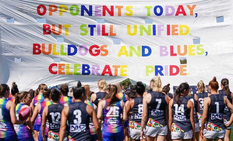Players run through the pride banner during the Round 3, 2020 AFLW match between the Western Bulldogs and Carlton Blues