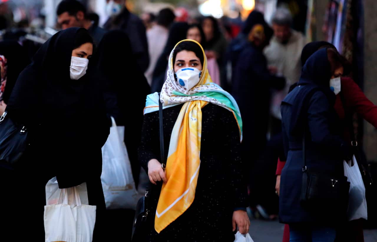 Iranians wearing face masks walk on a street of Tehran, Iran.