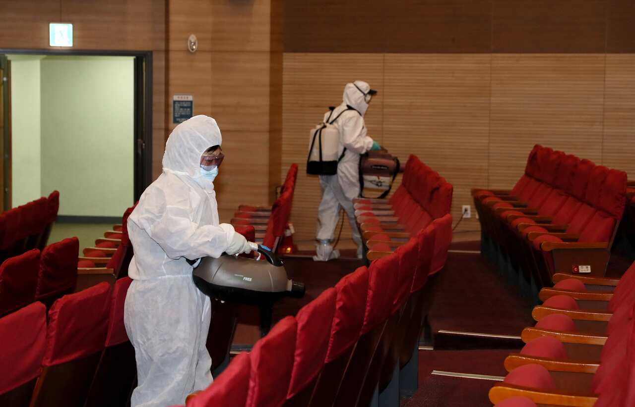 Health workers disinfect the main auditorium at the parliamentary member's office building in the National Assembly in Seoul, South Korea, 24 February 2020.