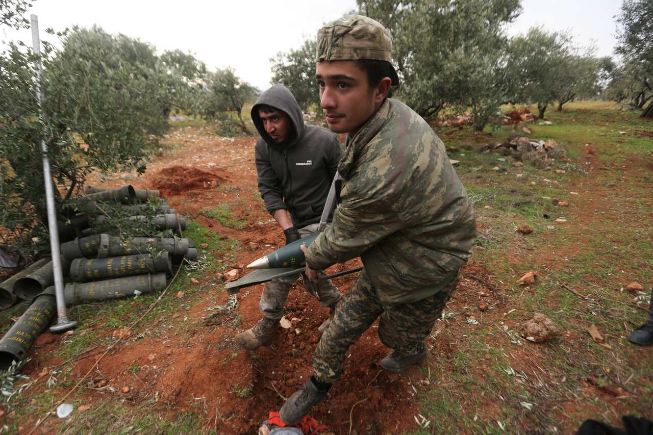 Turkish backed Syrian fighters prepare to fire a howitzer near the village of Neirab, in Idlib province, Syria. 