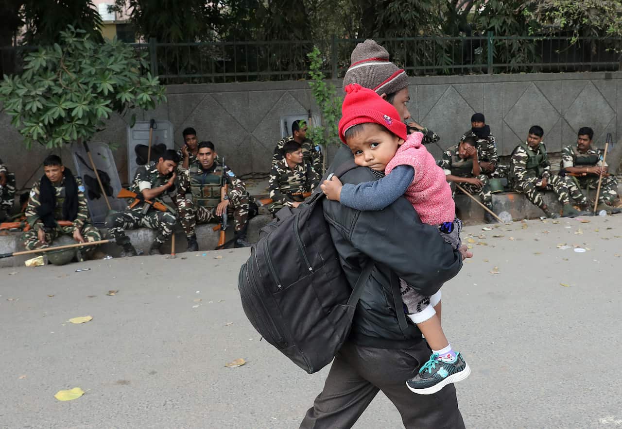 A man with his boy leaves for a safer place near after clashes in New Delhi, India.