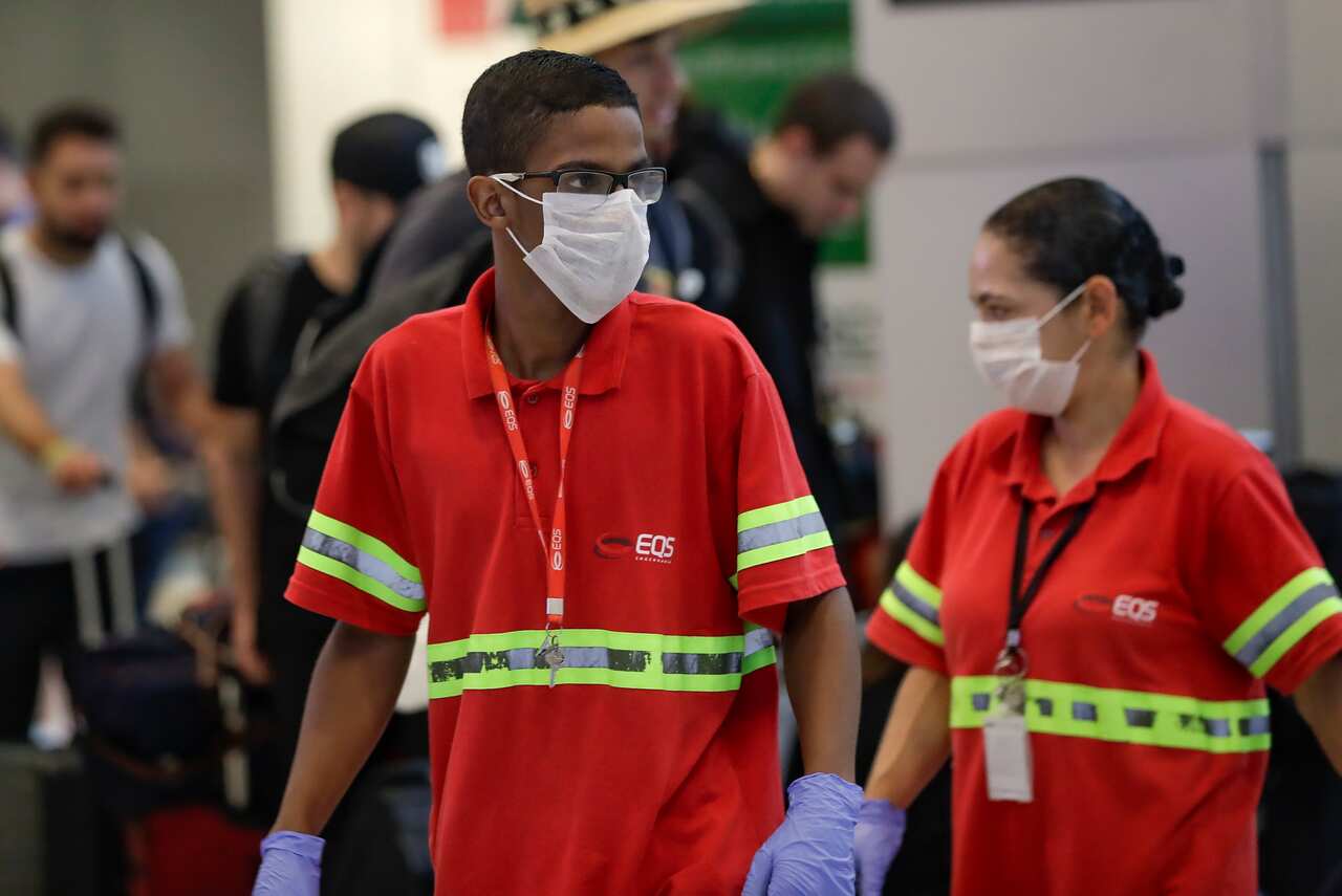 Airport employees wear masks as a precaution against the spread of the new coronavirus COVID-19 as they work at the Sao Paulo International Airport in Sao Paulo, Brazil, Wednesday, Feb. 26, 2020. (AP Photo/Andre Penner)