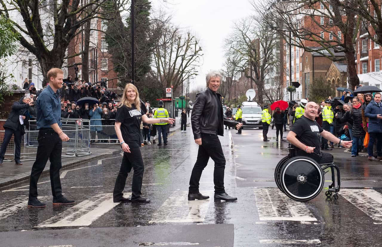 Prince Harry, Duke of Sussex, accompanied by Jon Bon Jovi and members of the Invictus Games choir, crosses the iconic Abbey Road zebra crossing.