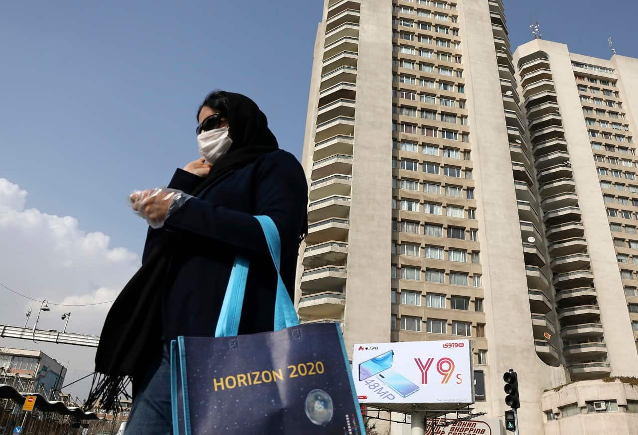 A pedestrian wearing a face mask crosses a street in northern Tehran.