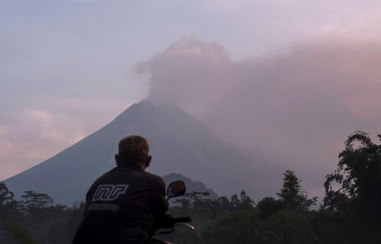 A man watches as Mount Merapi spews volcanic material into the air in Sleman.