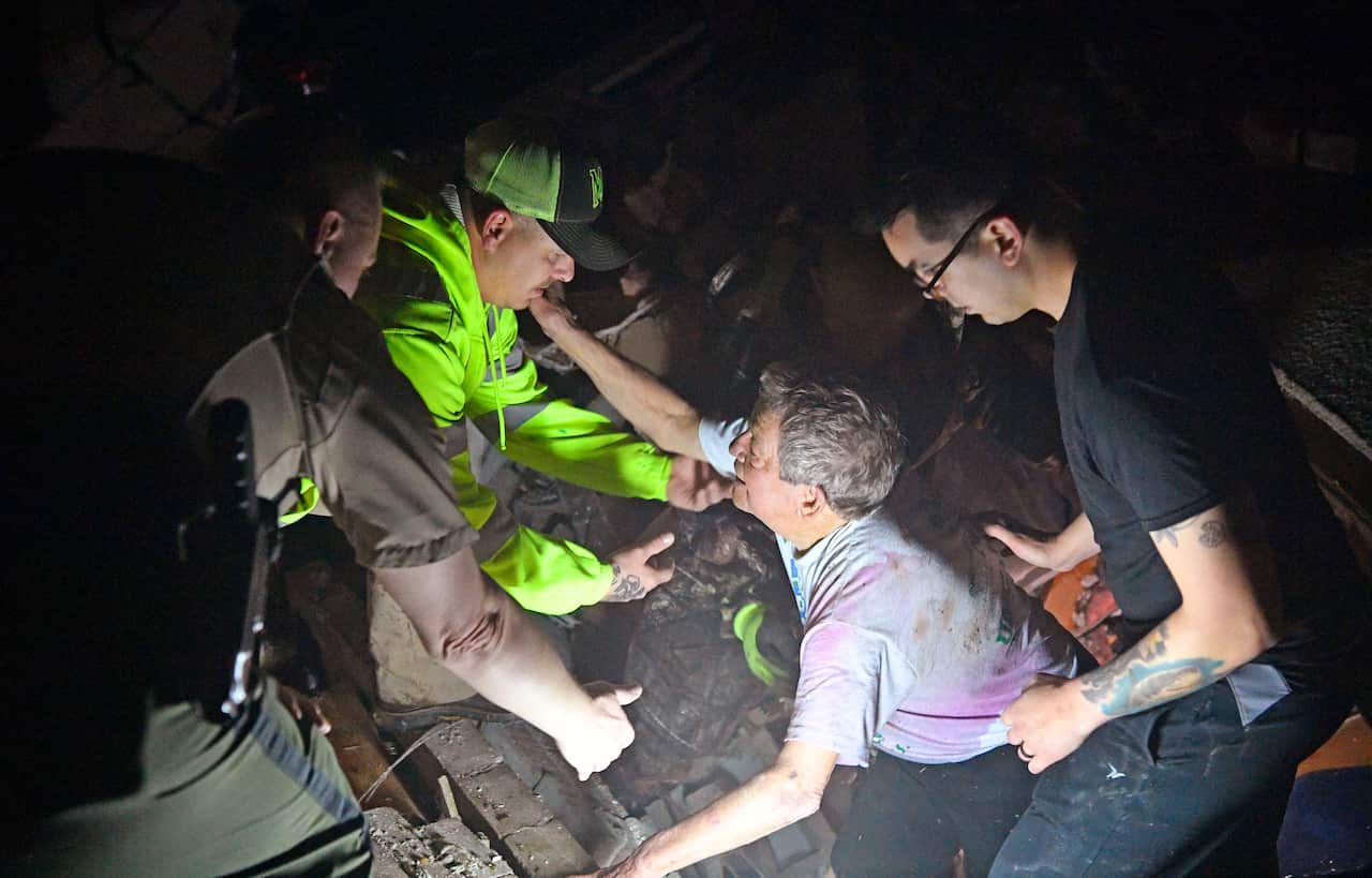 Bill Wallace reaches out to rescue workers who freed him home that collapsed on him and his wife trapping in Mt. Juliet, Tennessee. 3 March, 2020.