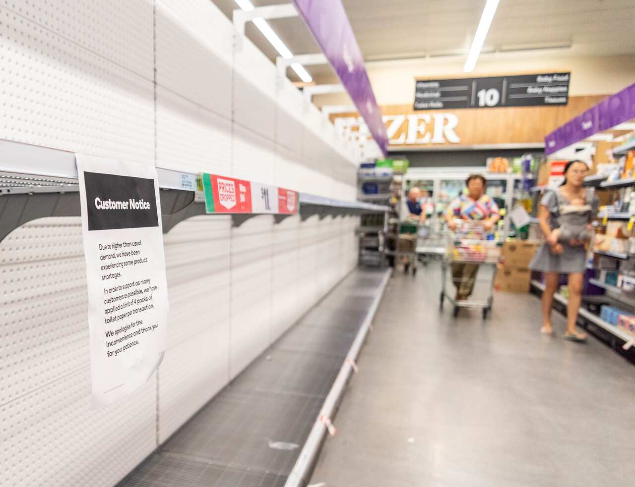 Customers looks at empty shelves at a supermarket.