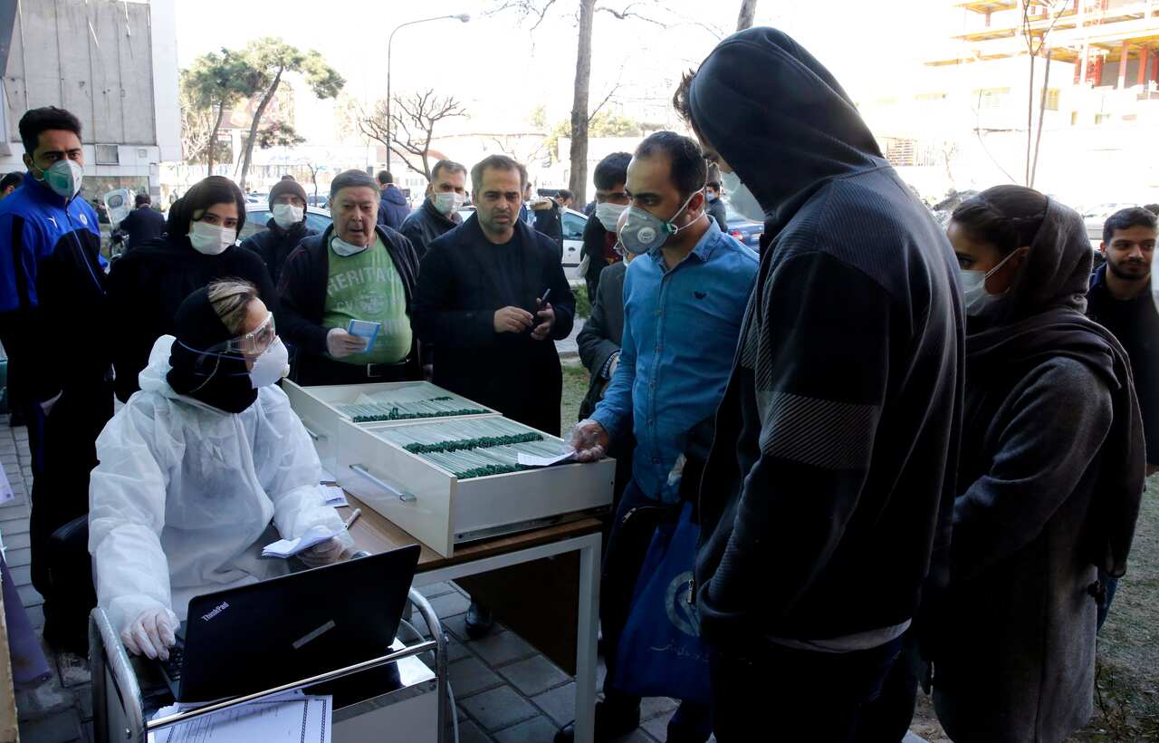An Iranian lab official registers people for Covid-19 coronavirus test outside a lab in Tehran, Iran