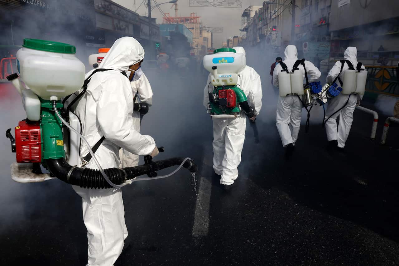 Firefighters disinfect a street against the new coronavirus, in western Tehran, Iran