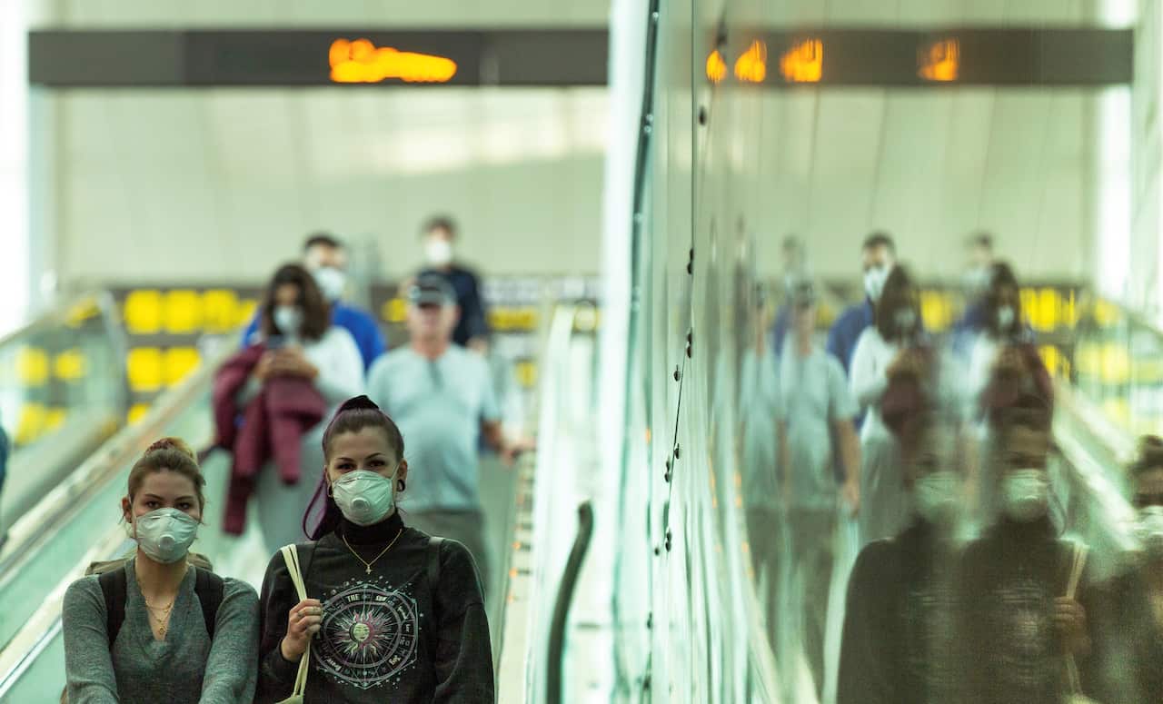 Travelers wear protective masks at the airport in Barcelona, Spain.