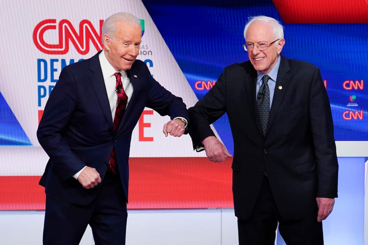 Former Vice President Joe Biden and Senator Bernie Sanders greet each other before participating in a Democratic presidential primary debate.