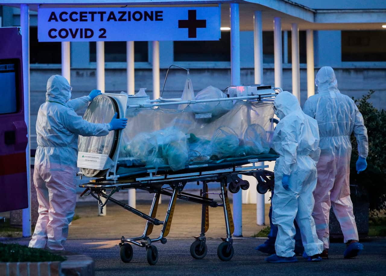 A patient on a stretcher is transported by medical workers wearing protective suits at Gemelli hospital in Europe.