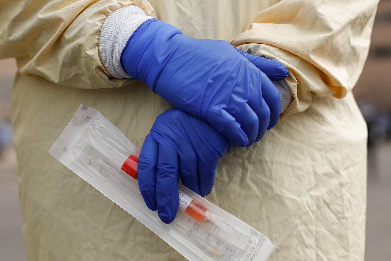 A nurse holds a swabs and test tube kit to test people for COVID-19.