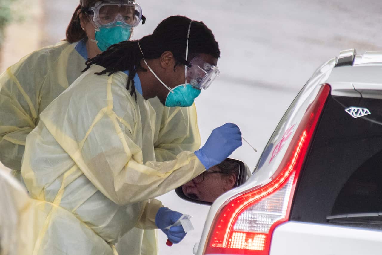 A health care professional applies a swab at a drive-thru coronavirus testing facility for residents Arlington, Virginia.