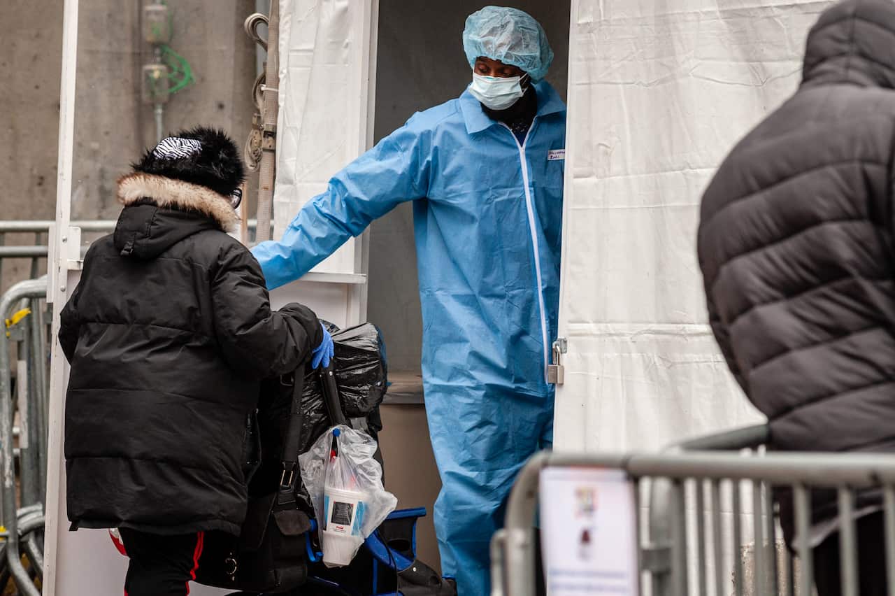 A staffer of The Brooklyn Hospital Center opens the door for a woman entering the outdoor tent facility where patients are pre-screened for the Coronavirus in Brooklyn, New York on March 19, 2020. (Photo by Gabriele Holtermann-Gorden/Sipa USA)