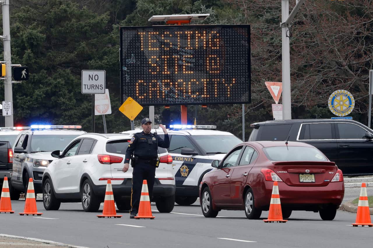 A police officer waves traffic past the entrance to a drive-through COVID-19 testing center after it reached capacity in New Jersey.