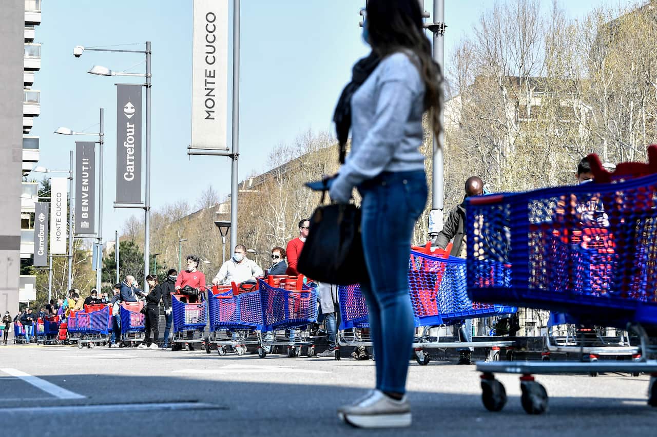People queue waiting to enter a supermarket in Turin, Italy, Saturday, March 21, 2020. For most people, the new coronavirus causes only mild or moderate symptoms. For some it can cause more severe illness. (Marco Alpozzi/LaPresse via AP)