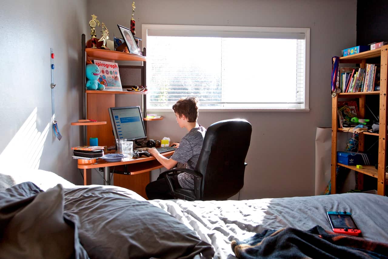 A student works on an online class assignment in his bedroom.