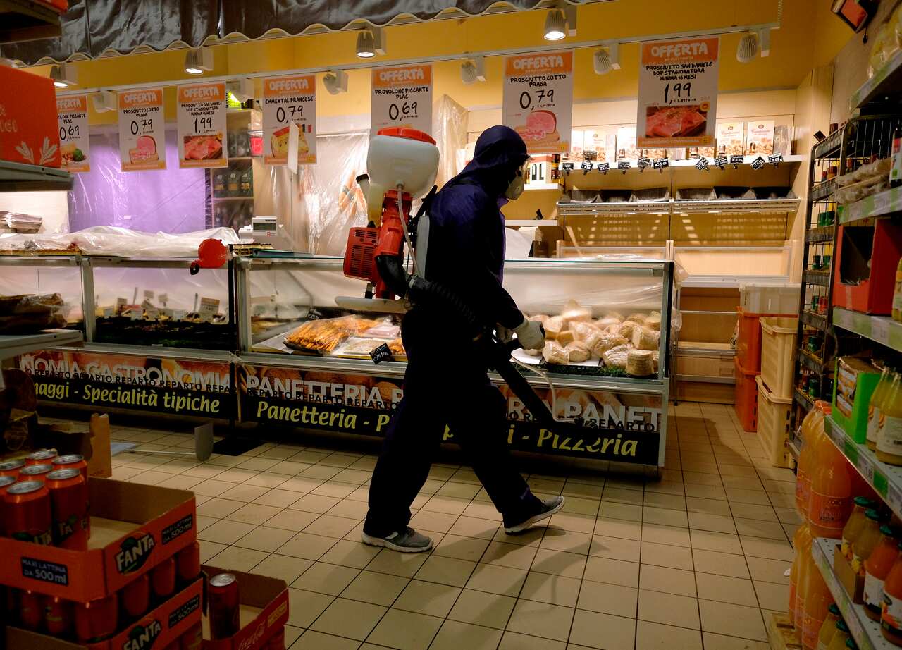 A man sanitizes a supermarket after closure, in Rome.