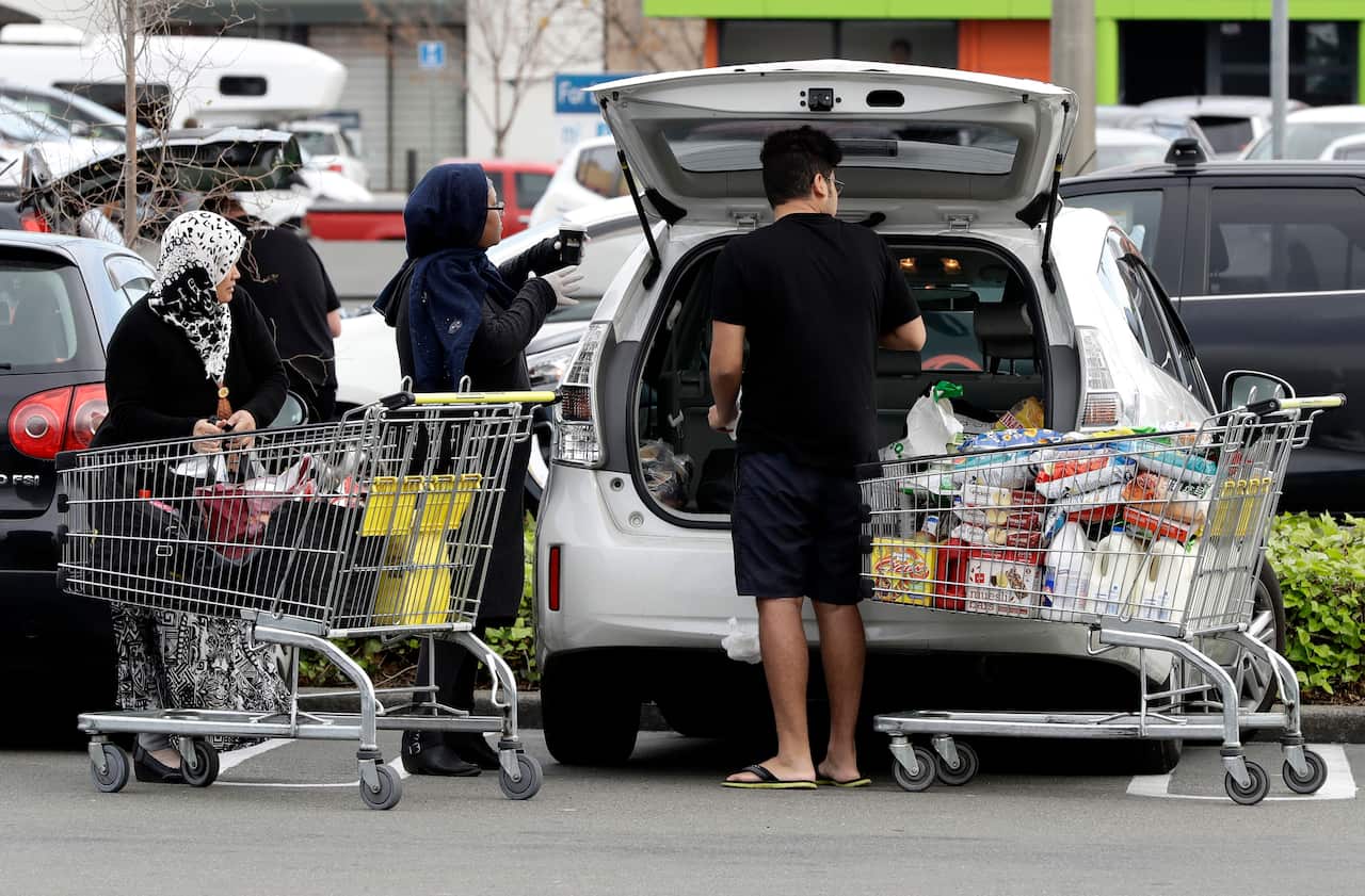 A family packs its shopping into their car in a supermarket in central Christchurch, New Zealand