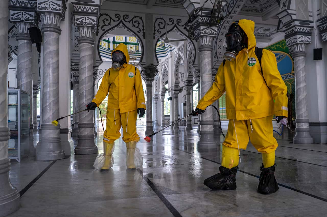 Volunteers from Prevention Task Force for COVID-19 Indonesia spray disinfectants at an Indonesian Mosque.