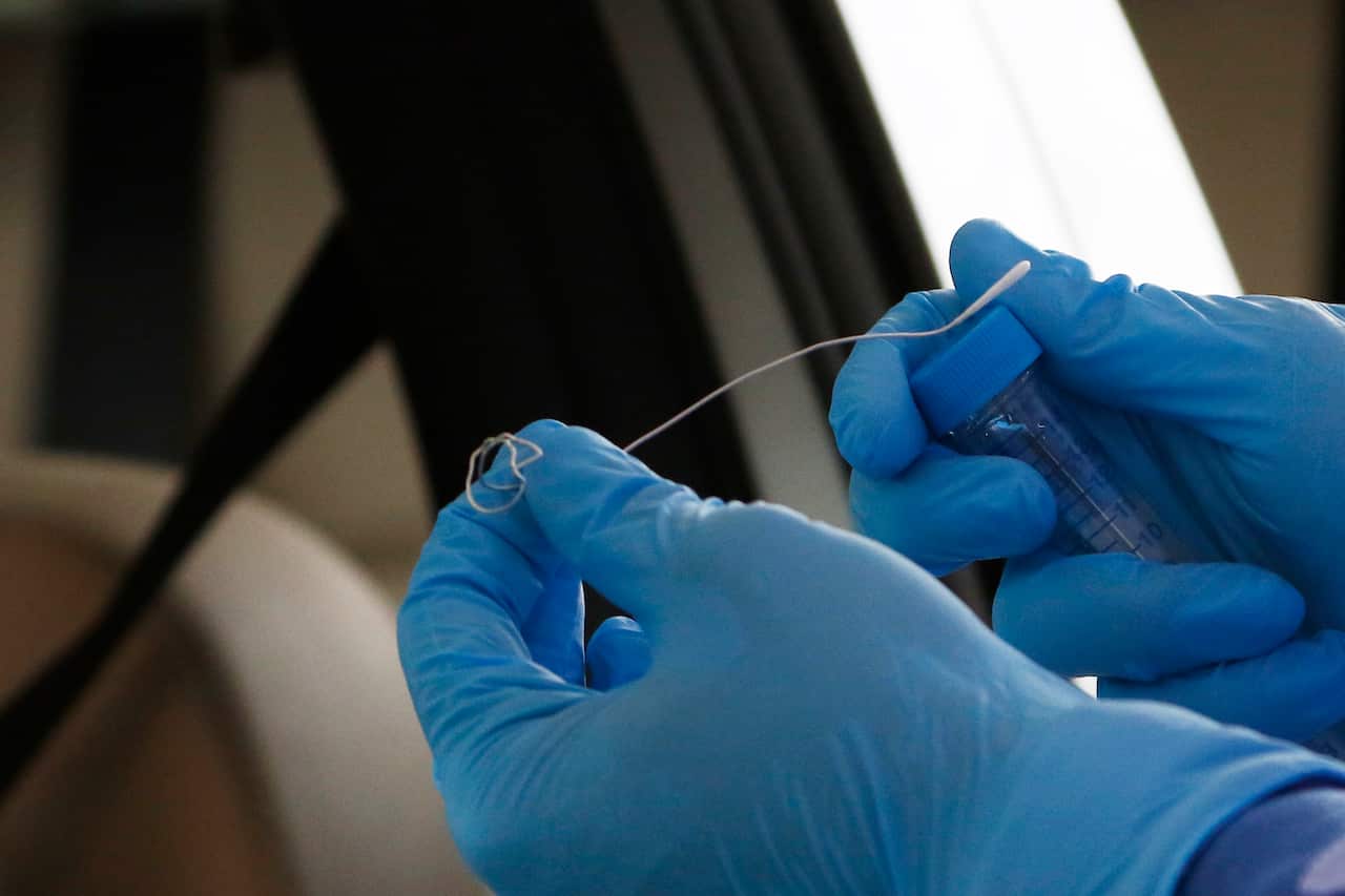 A practitioner collects a specimen for coronavirus testing.