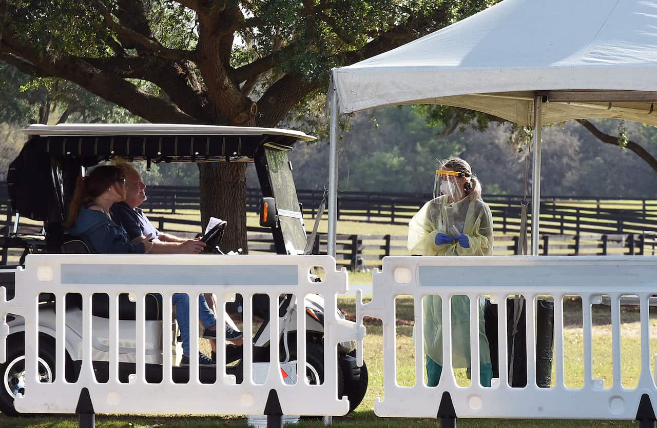 A couple arrives in a golf cart to be tested at a COVID-19 mobile testing site.