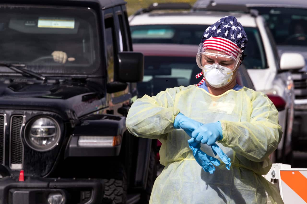 A nurse changes gloves each time she collects a sample from a patient at a drive through coronavirus testing site south of Los Angeles, California.