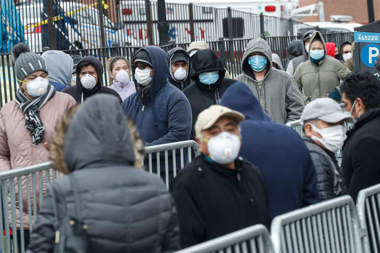 Patients wear personal protective equipment while maintaining social distancing as they wait in line for a COVID-19 test in New York