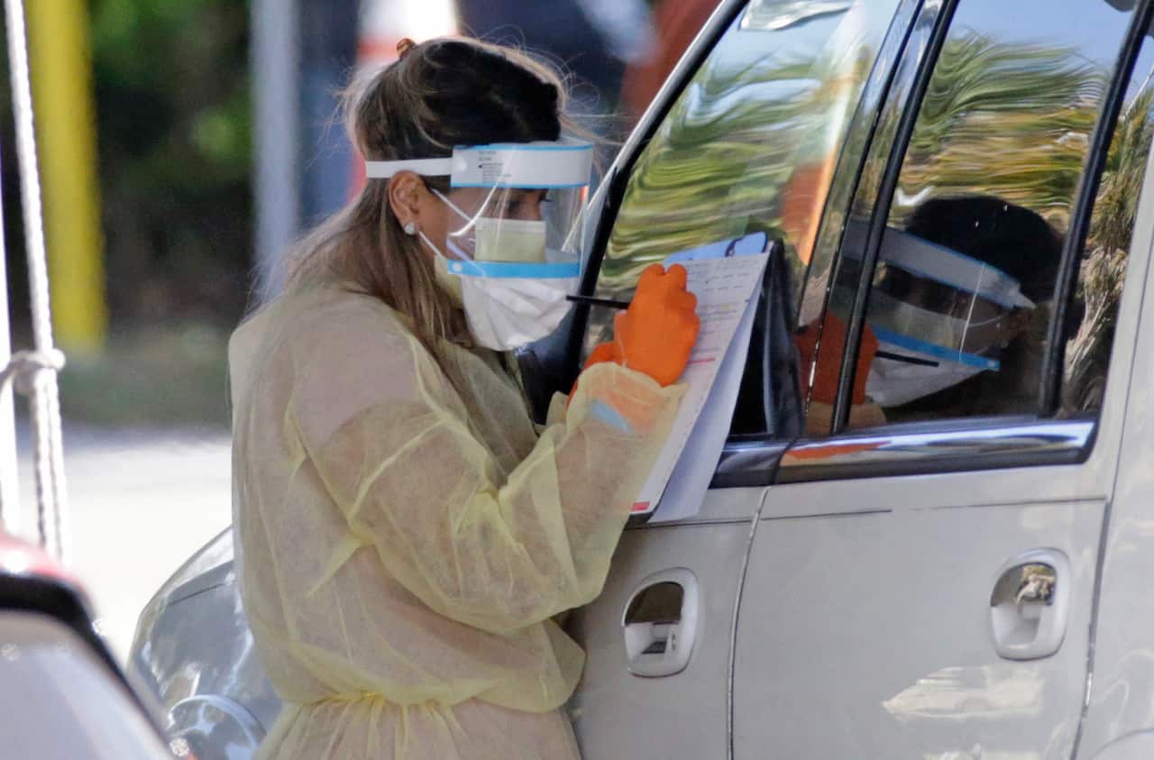 A Healthcare worker help to check in with the assistant from the Florida Army National Guard as vehicles line up at the COVID-19 drive-thru testing center at Marlins Park as the coronavirus pandemic continues on Wednesday, March 25, 2020 in Miami, FL, USA