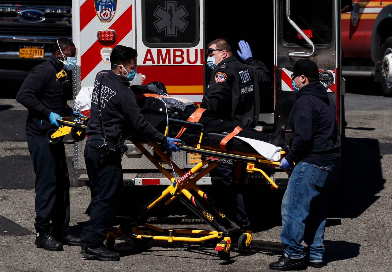 EMTs in protective masks bring a person into the emergency room in Queens, New York.