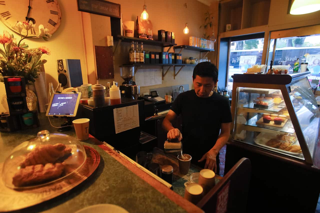 Cafe owner Marc Zheng serves a takeaway coffee at Le Petit Tarte Cafe in Sydney.